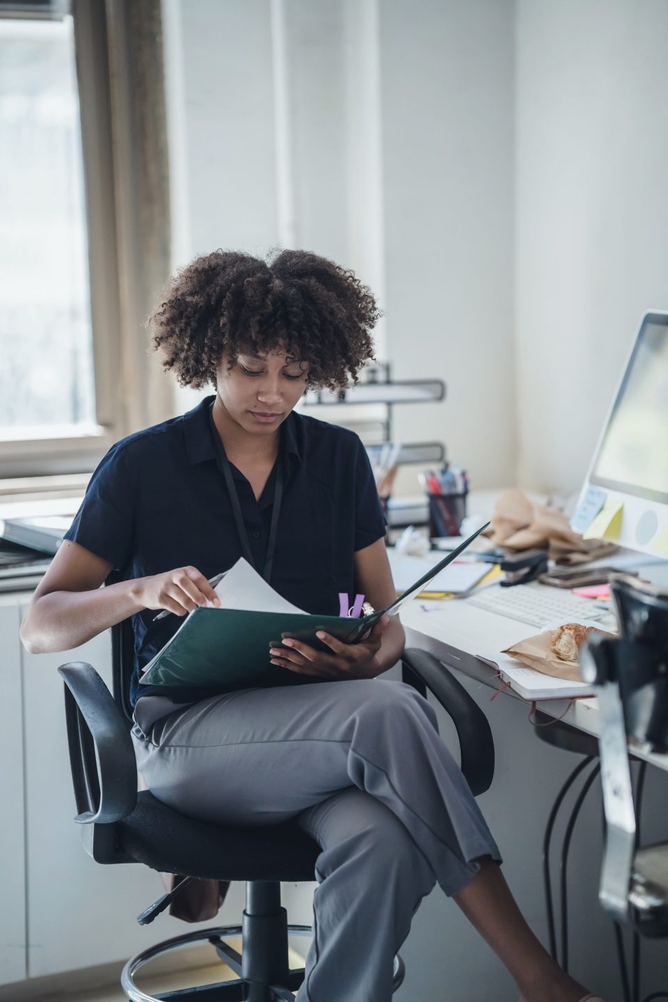 A woman in an office reading through a document in a folder